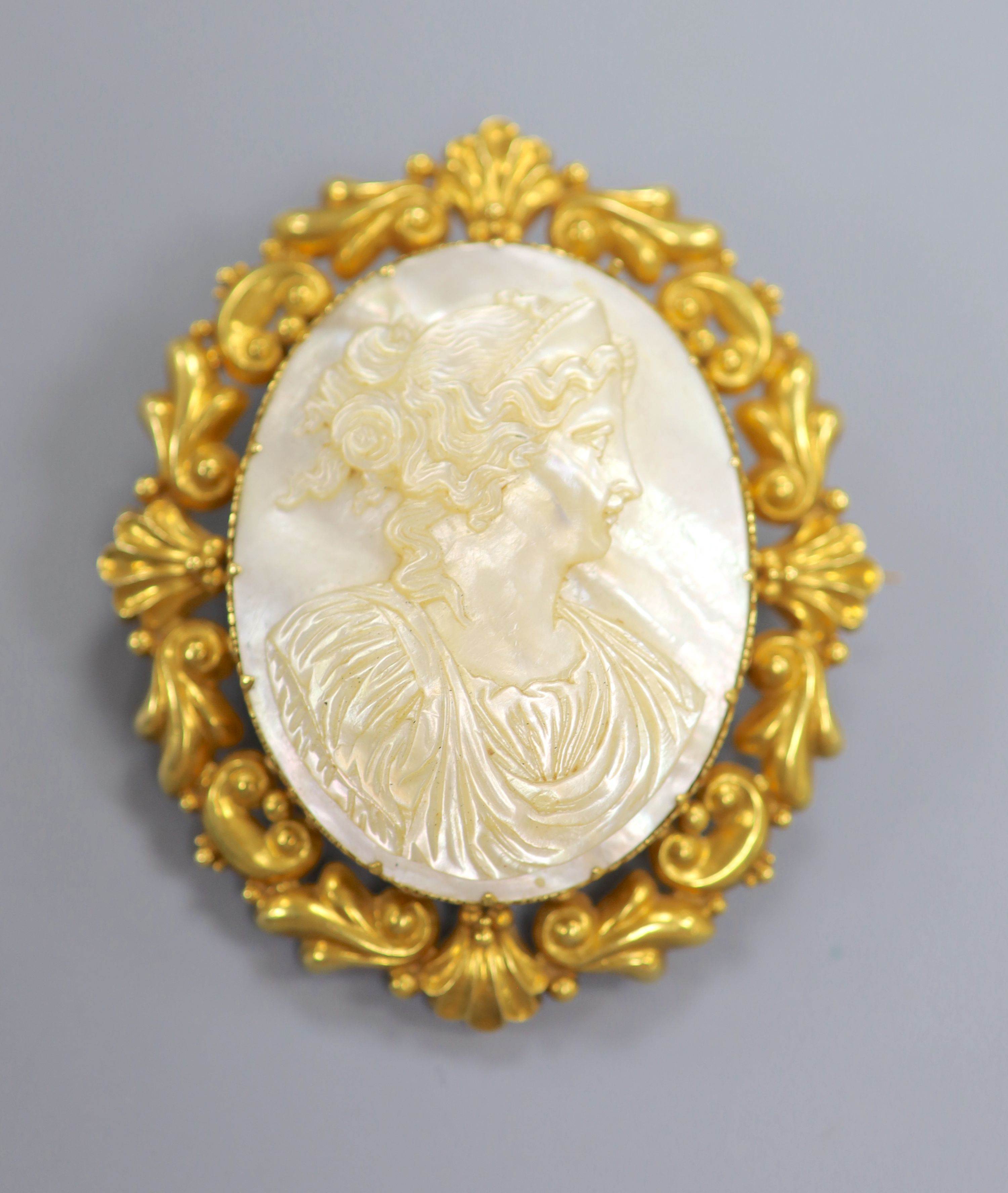 A yellow metal mounted carved mother of pearl cameo oval brooch, 59mm, gross 27.8 grams.